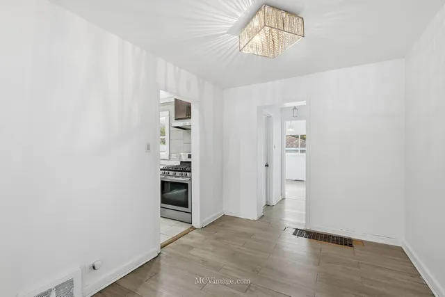 an empty room with wooden floor closet and windows