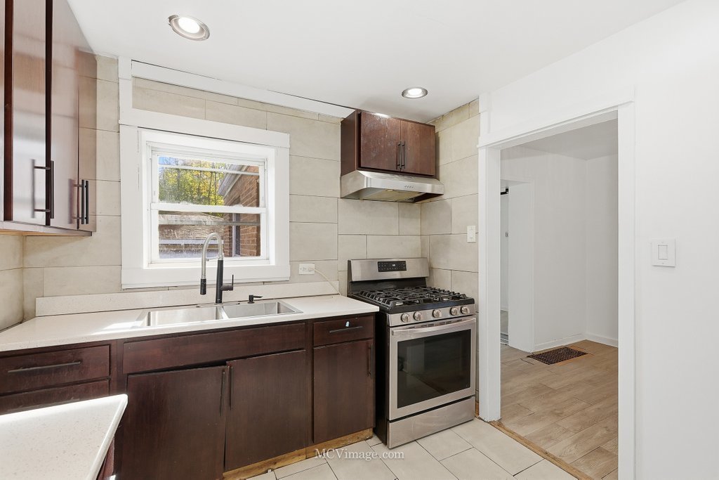 2161 East 97th Street Chicago, IL 60617 - Photo 6 of 13 a kitchen with stainless steel appliances a sink stove and cabinets