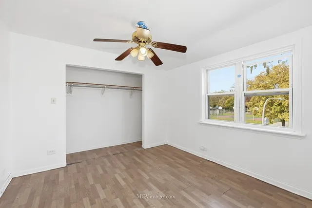 a view of empty room with wooden floor and fan