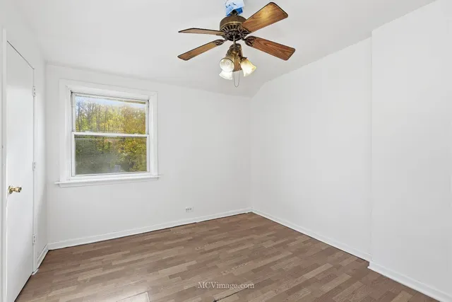 an empty room with window and ceiling fan