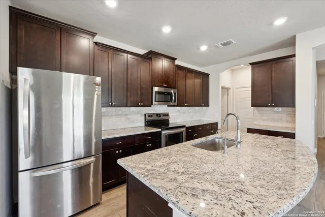 a kitchen with granite countertop a refrigerator and microwave