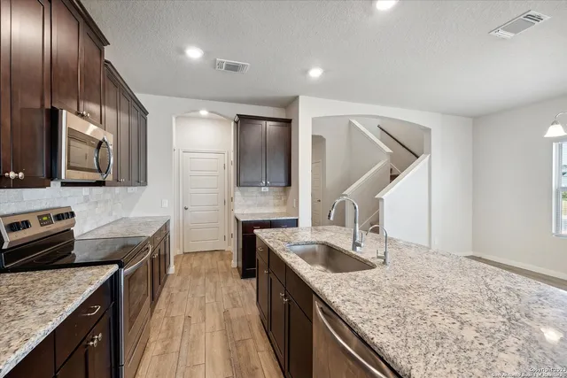 a kitchen with stainless steel appliances granite countertop a sink stove and refrigerator