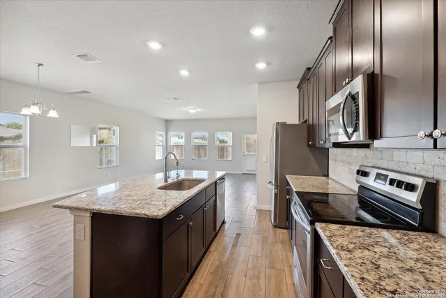 a kitchen with granite countertop kitchen island stainless steel appliances a sink stove and refrigerator