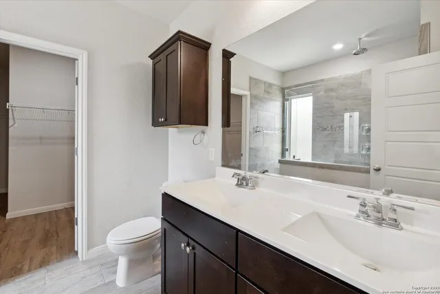 a bathroom with a sink a toilet a mirror and shower