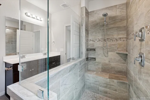 a bathroom with a glass shower sink and mirror