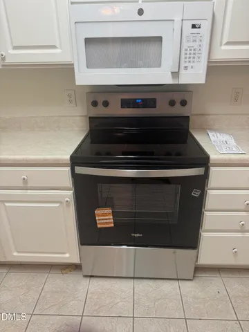 a kitchen with white cabinets and appliances