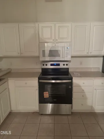 a view of a kitchen with white cabinets and refrigerator