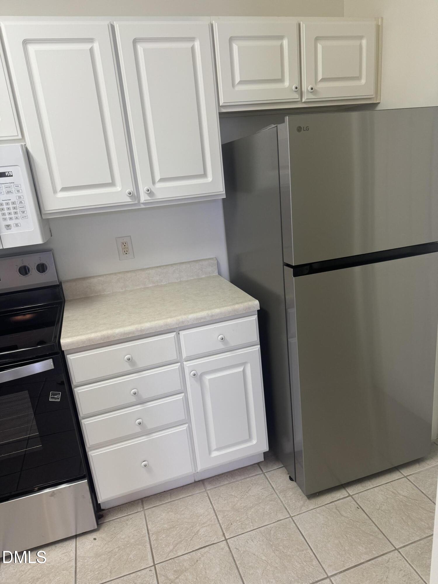 2511 Friedland Place, Unit 202 Raleigh, NC 27617 - Photo 7 of 19 a view of a kitchen with white cabinets and refrigerator