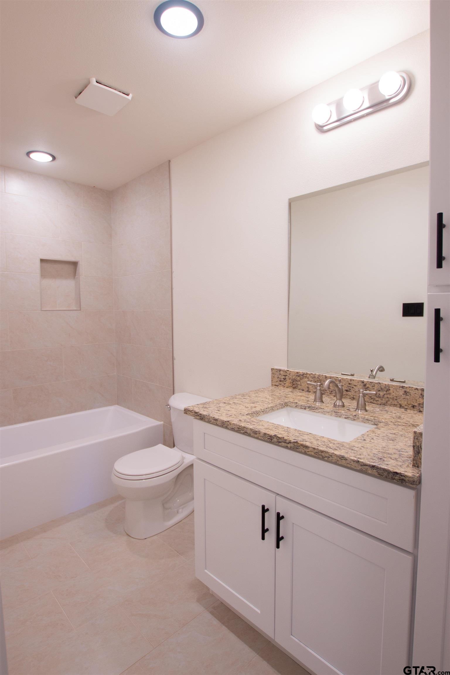 1108 Park Street Tyler, TX 75702 - Photo 16 of 27 a bathroom with a granite countertop sink a toilet a mirror and bathtub