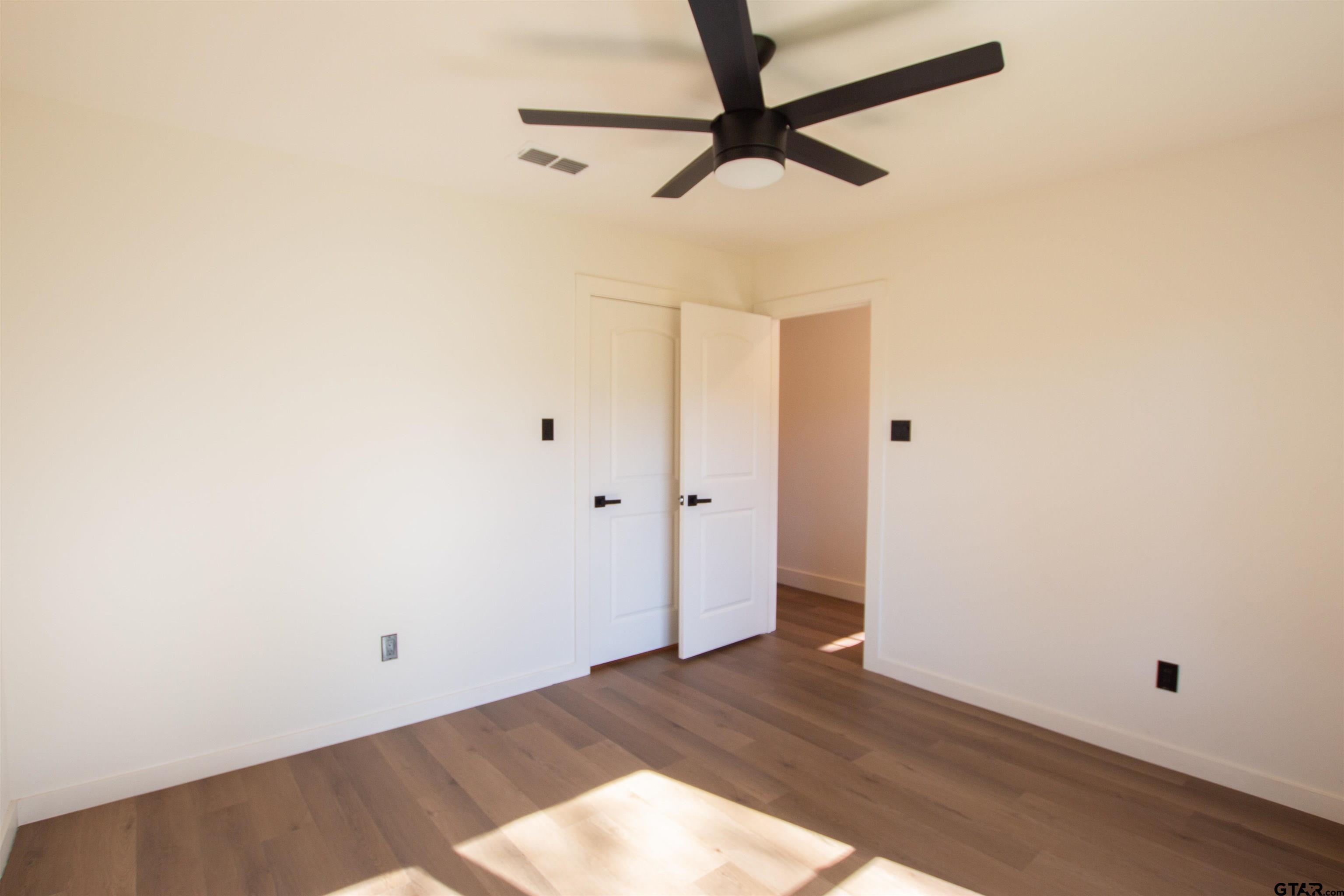 1108 Park Street Tyler, TX 75702 - Photo 17 of 27 an empty room with wooden floor and a ceiling fan