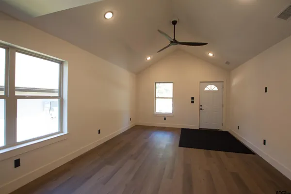 an empty room with wooden floor and windows