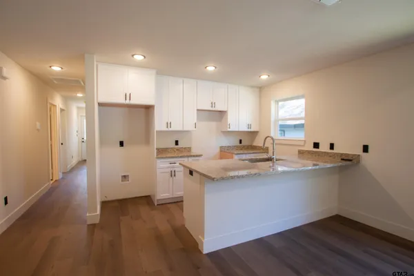 a kitchen with stainless steel appliances granite countertop a sink a stove a refrigerator and island with wooden floor