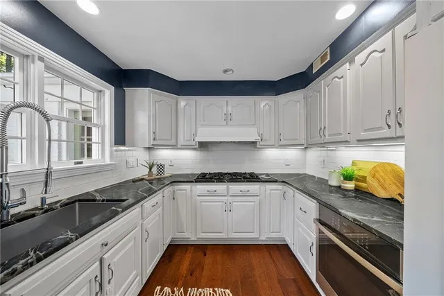 a kitchen with granite countertop white cabinets and white appliances