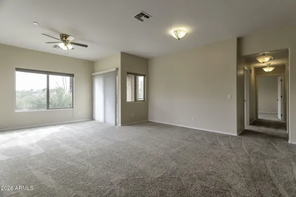 an empty room with windows and chandelier fan