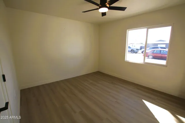 a view of an empty room with window and wooden floor
