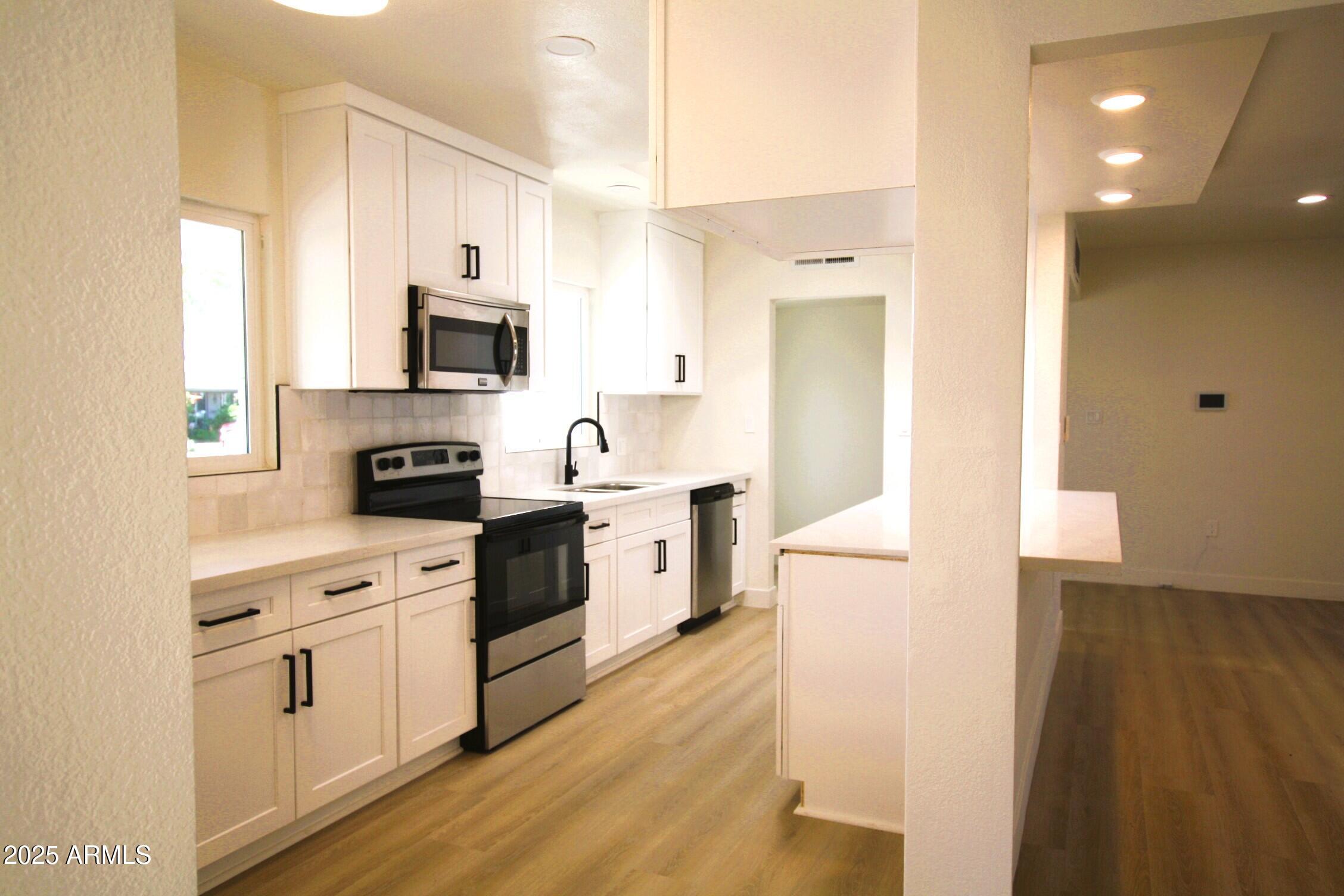 443 North Sycamore Mesa, AZ 85201 - Photo 7 of 33 a kitchen with stainless steel appliances a stove top oven a sink a refrigerator white cabinets and wooden floor