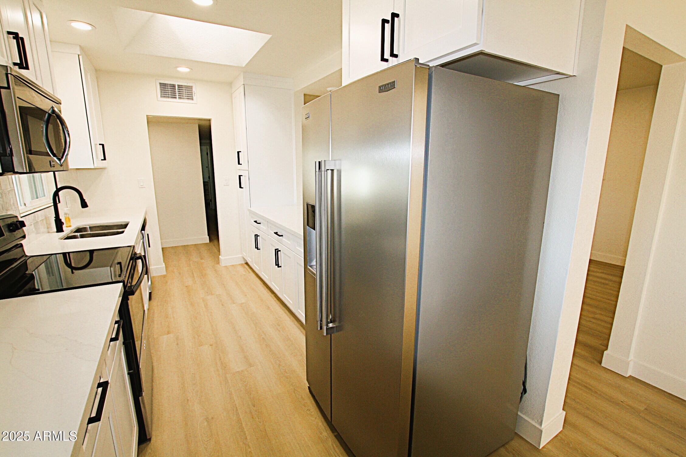 443 North Sycamore Mesa, AZ 85201 - Photo 9 of 33 a kitchen with stainless steel appliances a refrigerator a sink a stove top oven a wooden floor and cabinets