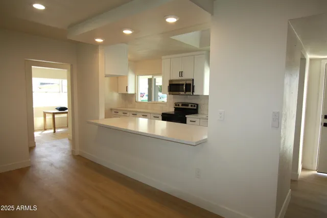 a view of a kitchen with kitchen island a sink wooden floor and a counter top space