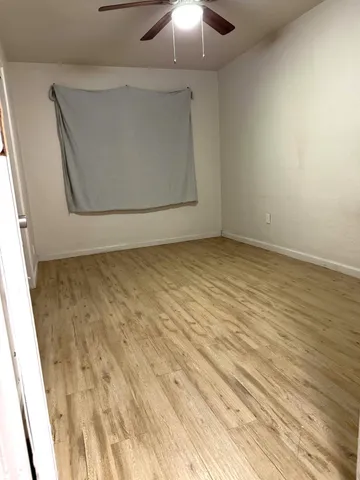 en empty room with wooden floor and fan