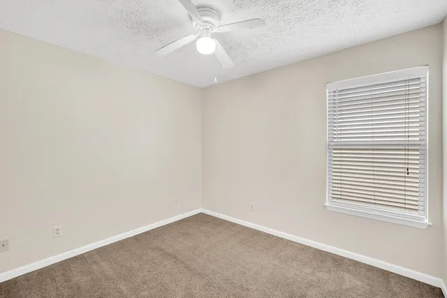 an empty room with a window and a fan