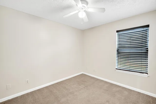 an empty room with a window and a fan