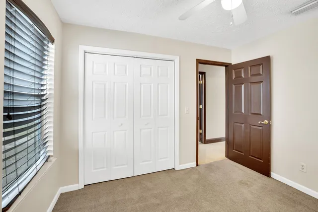 an empty room with a ceiling fan and windows