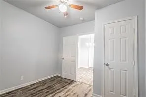 an empty room with wooden floor closet and windows