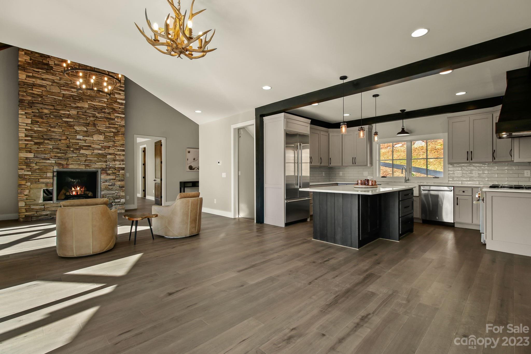 1736 Twin Rivers Drive Boone, NC 28607 - Photo 8 of 48 a large kitchen with stainless steel appliances kitchen island granite countertop a large refrigerator a sink dishwasher and a fireplace with wooden floor