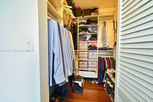 a view of walk in closet with clothes and shoes