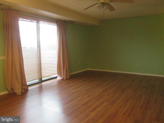 550 Heather Ridge Drive, Unit M Frederick, MD 21702 - Photo 4 of 9 an empty room with wooden floor and windows with curtains