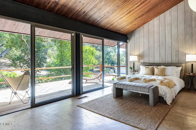 a bedroom with a bed and a large window with outer view