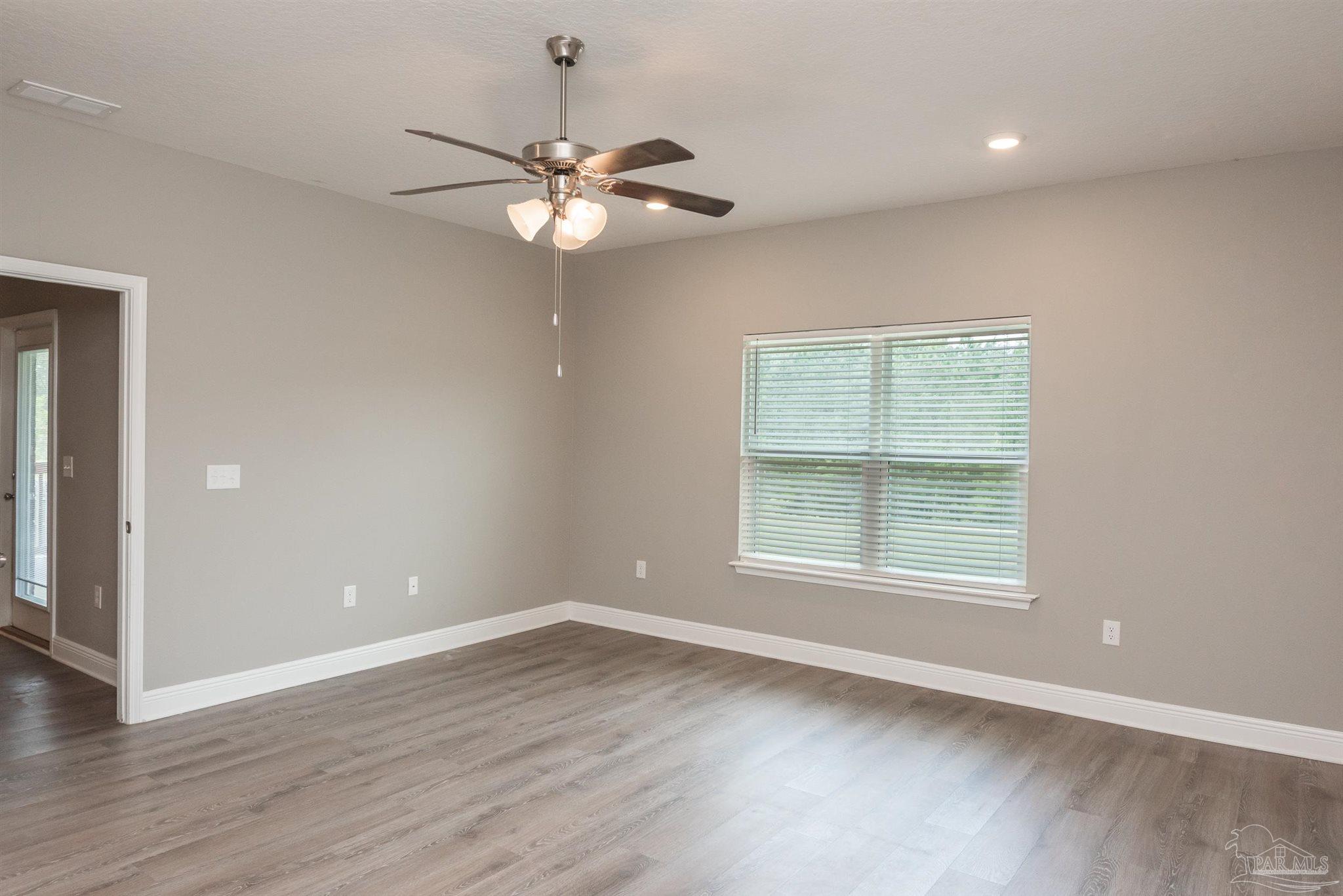 7882 Burnside Loop Pensacola, FL 32526 - Photo 20 of 28 an empty room with wooden floor chandelier fan and windows