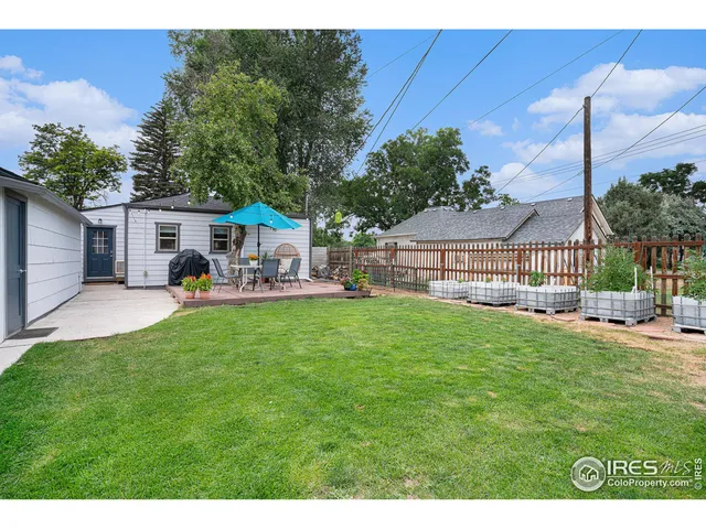 a view of a small house and a yard and furniture