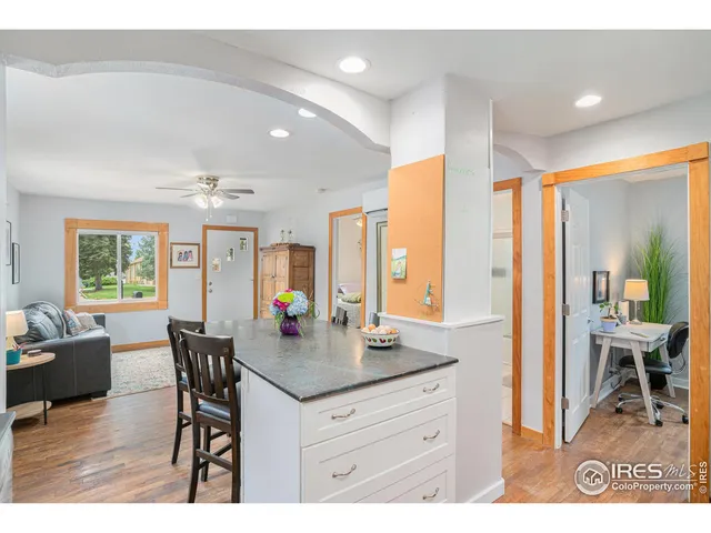 a dining hall with stainless steel appliances kitchen island granite countertop a table chairs and couches