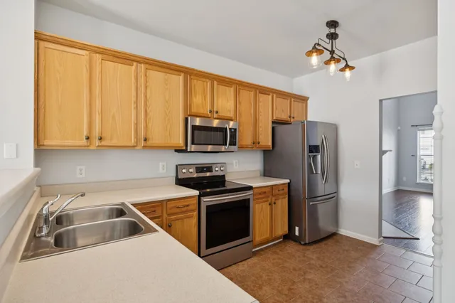 a kitchen with stainless steel appliances granite countertop a refrigerator oven a sink dishwasher and white cabinets with wooden floor