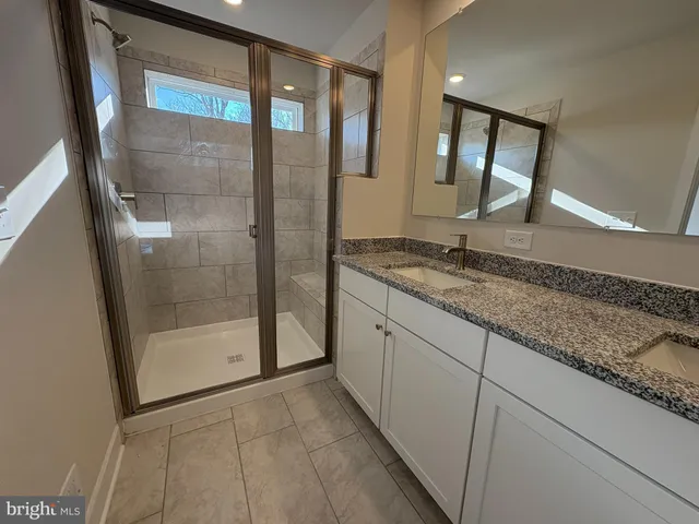 a bathroom with a granite countertop sink a mirror and shower