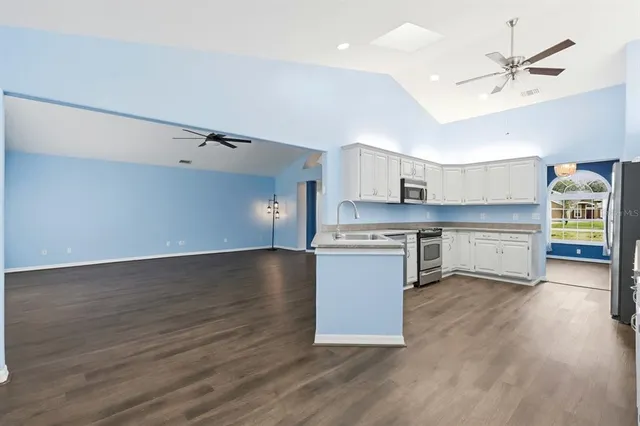 a kitchen with stainless steel appliances a stove top oven a sink dishwasher and a refrigerator with wooden floor