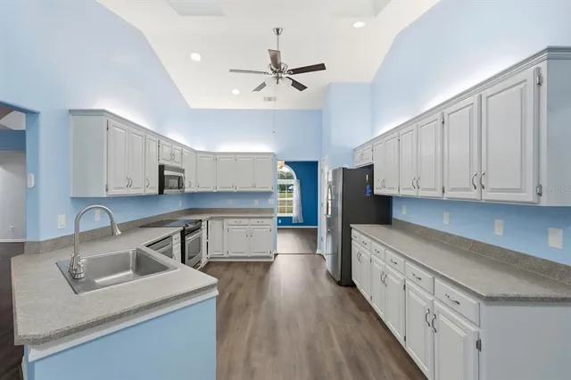 a kitchen with stainless steel appliances granite countertop a sink dishwasher stove and refrigerator with wooden floor