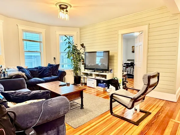 a living room with furniture a flat screen tv and a window
