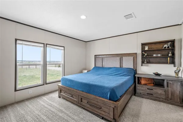 a bedroom with a bed a table and windows