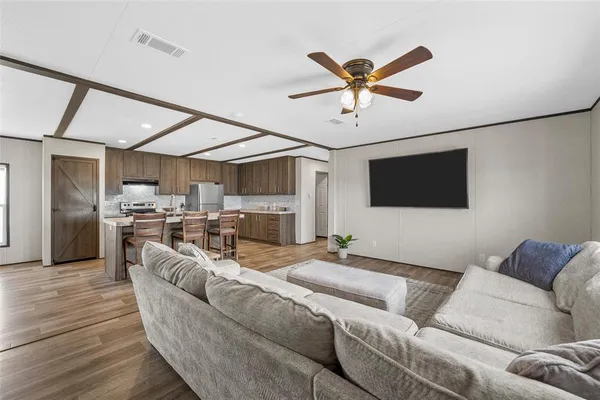 a living room with furniture kitchen and a flat screen tv