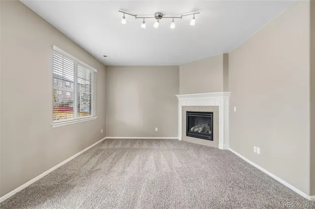 a view of an empty room with a window and fireplace
