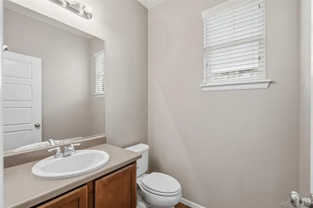 a bathroom with a granite countertop sink toilet a mirror and a window
