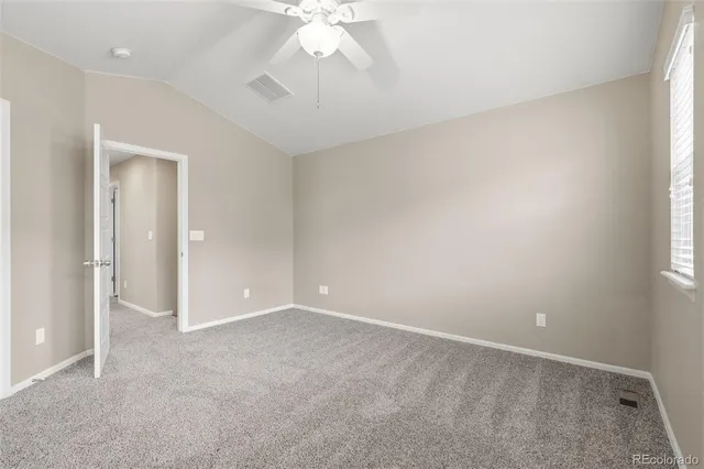 an empty room with a chandelier fan and windows
