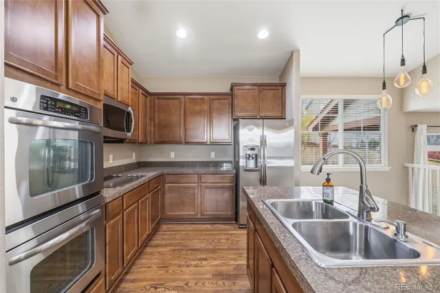 a kitchen with stainless steel appliances granite countertop a sink a stove and a wooden cabinets