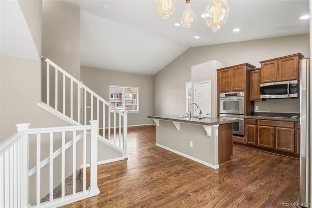 a view of kitchen with stainless steel appliances wooden floor and a refrigerator