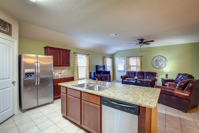 a kitchen with granite countertop a sink cabinets and stainless steel appliances