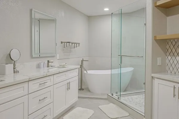 a spacious bathroom with a double vanity sink a mirror and a bathtub