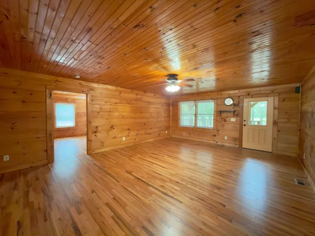 a view of an empty room with window and wooden floor