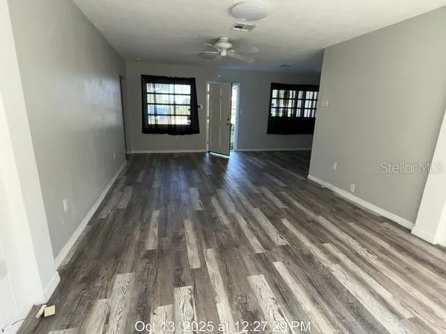 an empty room with wooden floor and windows